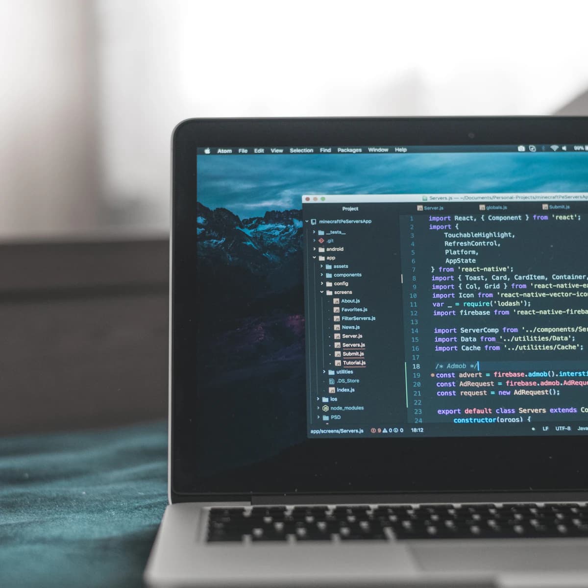 A laptop displaying React Native application code in a development workspace